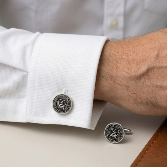 Cufflinks on a white shirt cuff with a close-up of one cufflink on a surface.