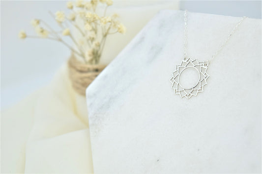 a silver-colored choker necklace with a geometric design, representing the Sahasrara Yoga chakra.
