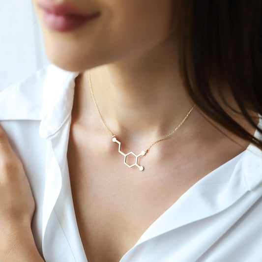 Gold molecular structure necklace on a white background on a model.