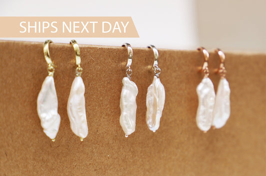 A close-up image of 3 pairs of drop baroque pearl earrings in silver gold and rose gold hoop.