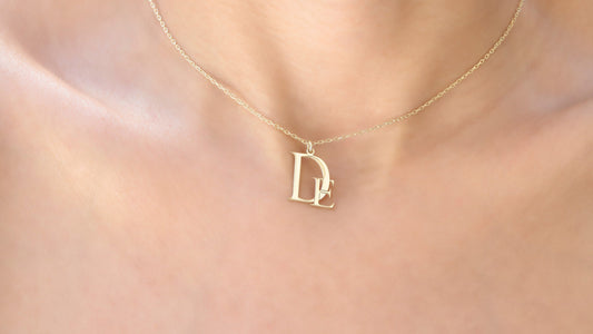 A gold-colored necklace with a pendant in the shape of a letter 'D' on a person's neck.