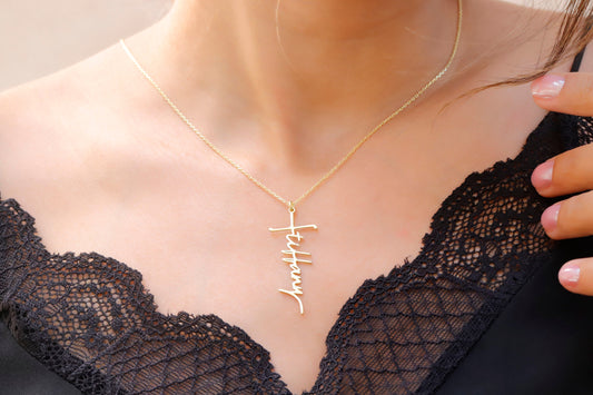 A close-up image of a woman wearing a personalized cross name necklace with the word 'Faith' inscribed on a gold faith cross pendant.