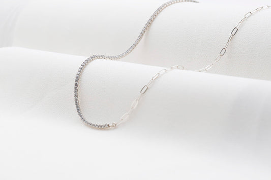 A close-up image of a silver tennis and paperclip chain necklace.