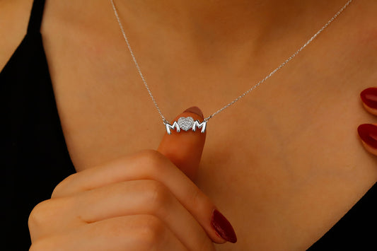 Necklace with a unique design held by a hand against a neutral background