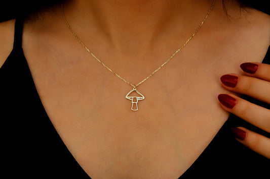 Gold necklace with a pendant worn by a person, with a hand touching the chest.