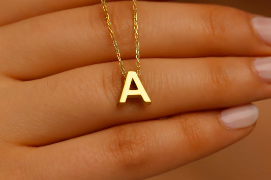 Gold necklace with a 'A' pendant on a hand