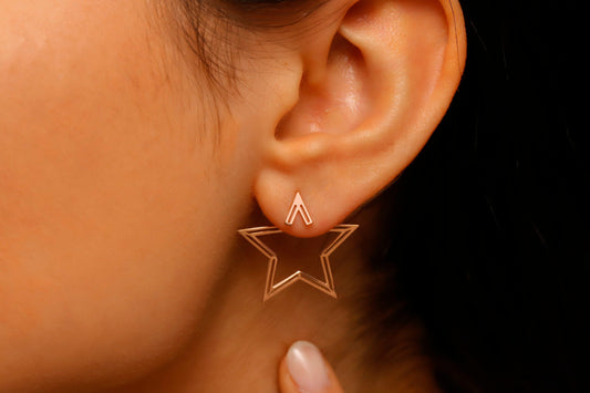 Star-shaped earring worn on an ear with a dark background