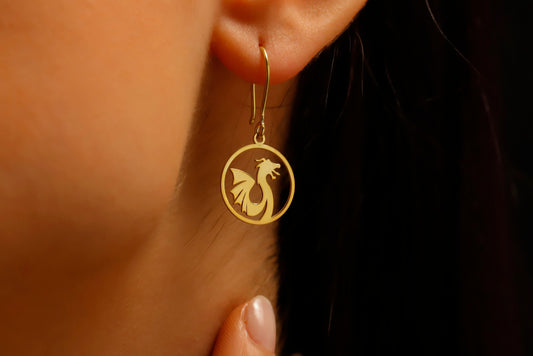 Gold earring with a dragon design worn by a person.