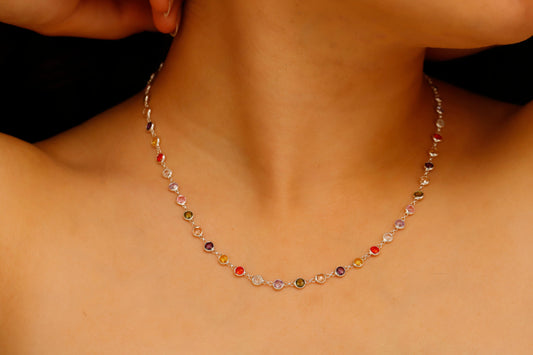 A multicolor baguette cut gemstone necklace with a silver finish, displayed on a person's neck.