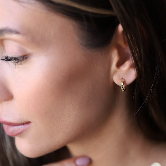 A close-up image of a person wearing a silver hoop earring with a small gold detail on the hoop.