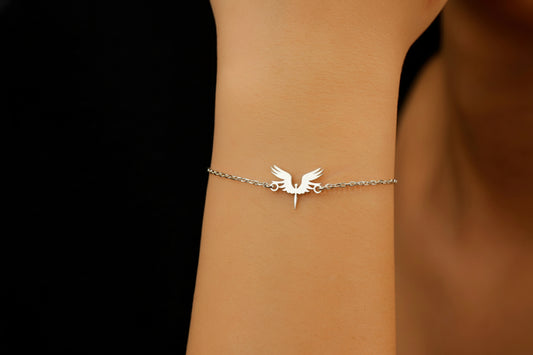 A bracelet with a 14K gold charm in the shape of a phoenix bird, displayed on a person's wrist.