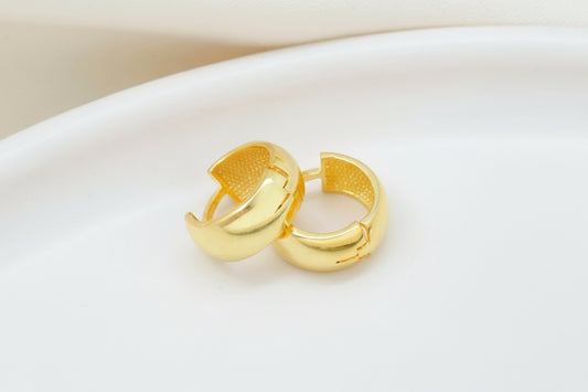 Pair of gold hoop earrings on a light beige background