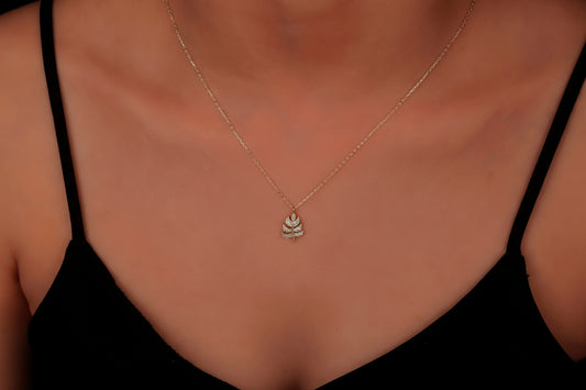 Necklace with a leaf pendant on a person wearing a black top.