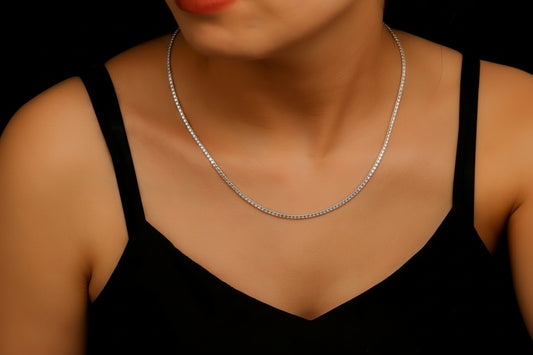 A person wearing a silver tennis choker diamond necklace with a v-neck black top.
