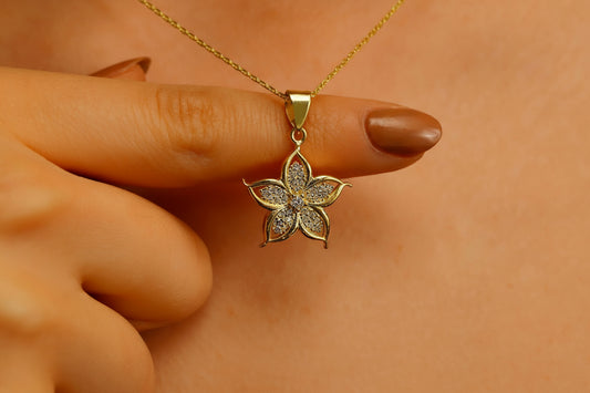 A gold-filled necklace with a lily flower pendant, worn by a person.