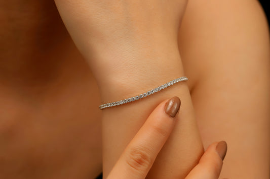 Silver tennis bracelet on a wrist with a blurred background