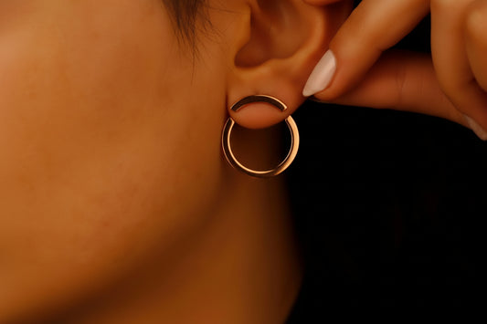 Close-up of a person wearing a rose gold hoop ear jacket earrings.