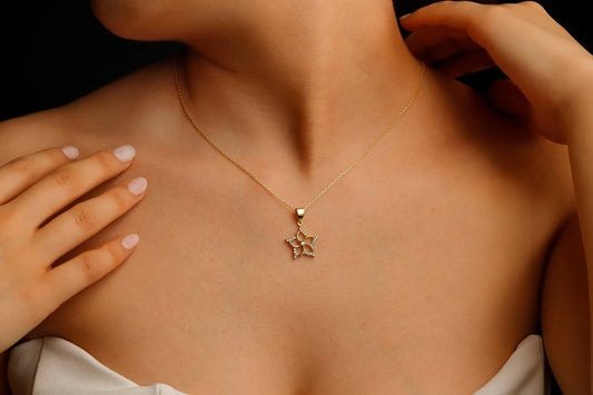 A close-up image of a woman wearing a silver necklace with a gold-colored star-shaped pendant.