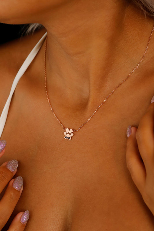 A close-up image of a person wearing a gold-filled paw-shaped necklace with a custom animal name pendant.