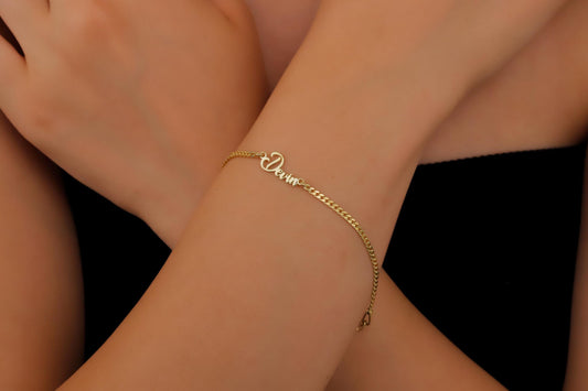 A close-up image of a person wearing a personalized name bracelet with a chain link design in silver.