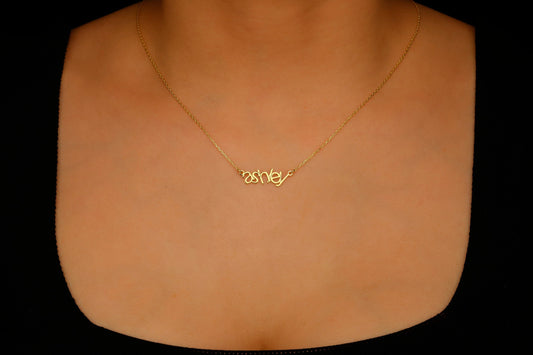 Gold necklace with a name pendant on a mannequin neck against a black background