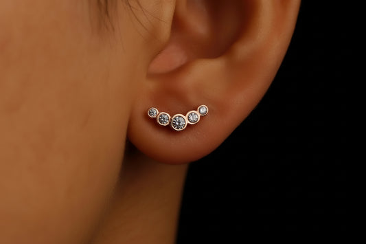 Close-up of an ear wearing a set of diamond stud earrings against a black background