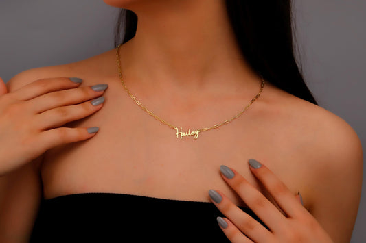 A woman wearing a dainty personalized name necklace in gold finish.