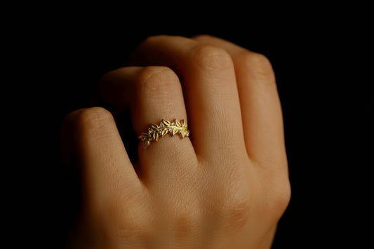 A person's hand showcasing a gold-filled olive leaf ring with pave, featuring a leaf design.