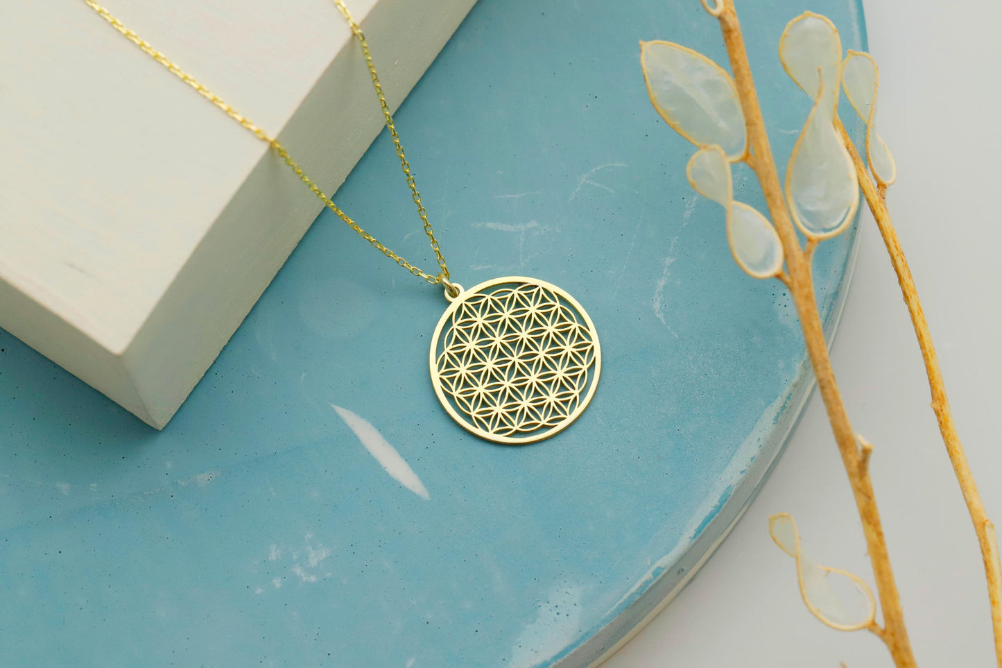 Gold necklace with a geometric pendant on a blue surface