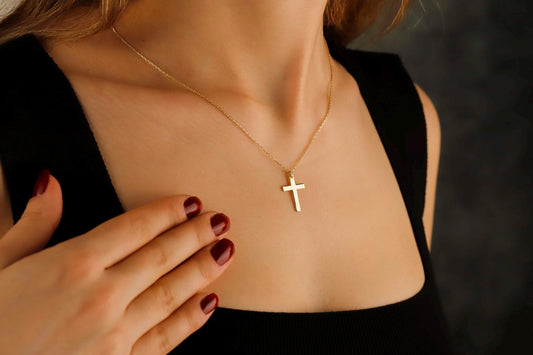 Gold cross necklace on a person with a blurred background