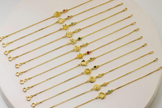 Gold flower necklaces and bracelets with various charms on a white heart-shaped stand