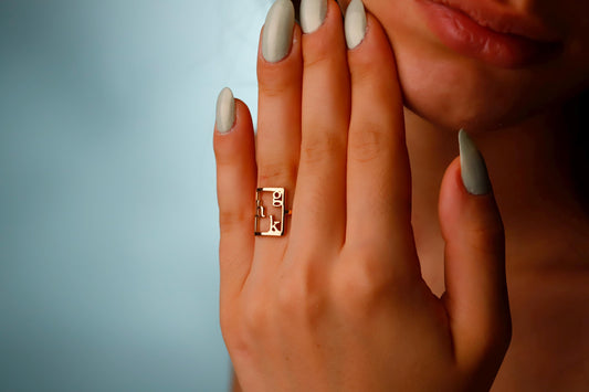 Close-up of a hand wearing a gold ring with a blue background