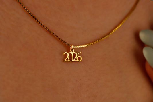 Gold necklace with '2026' pendant on a blurred background
