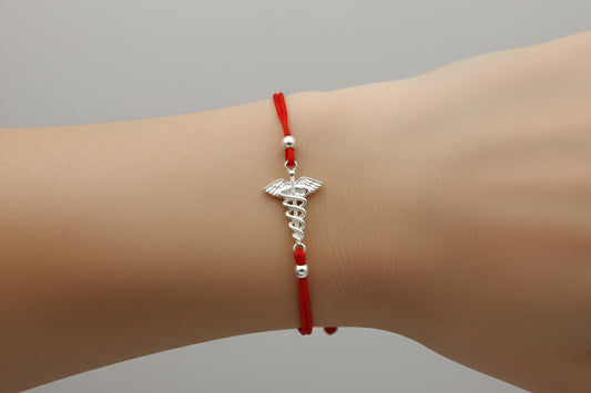 Red bracelet with a silver medical symbol on a wrist against a gray background