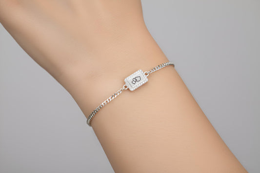 Silver bracelet with a clasp on a person's wrist against a gray background