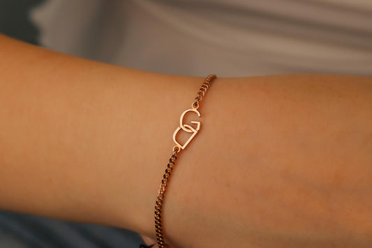 Rose gold bracelet with a heart design on a wrist against a neutral background