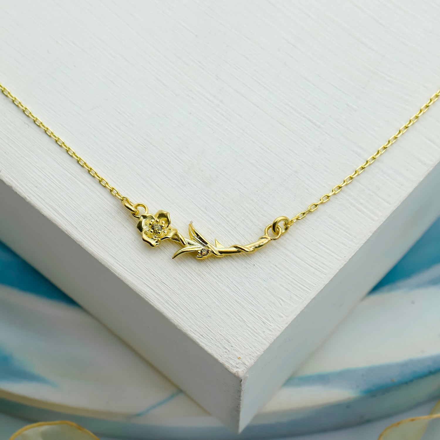 Gold necklace with floral design on a ceramic plate