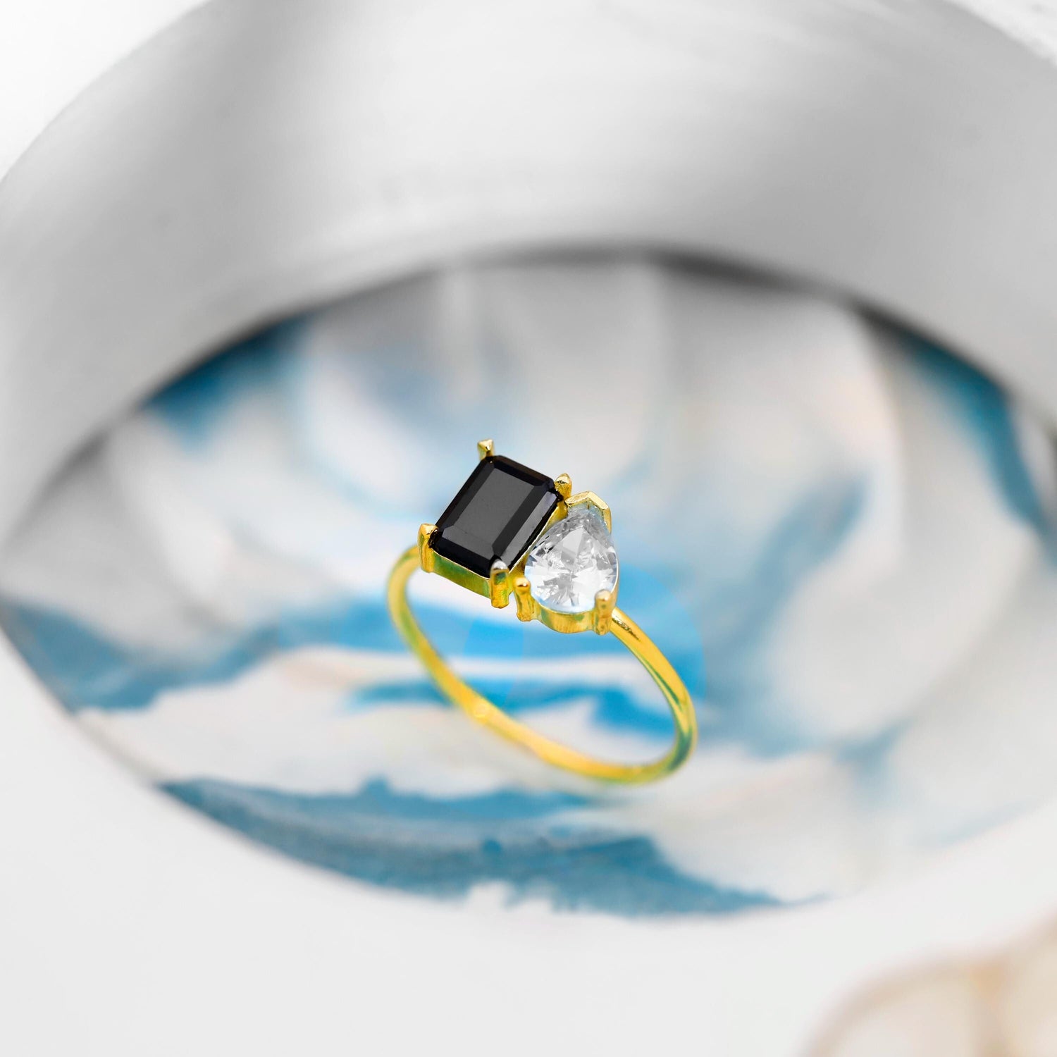 Gold ring with a black gemstone and clear stones on a blurred background