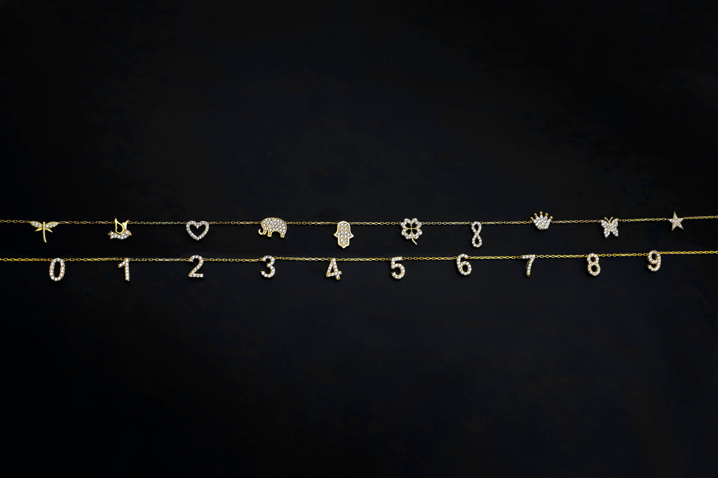Gold jewelry charms including numbers, animals, and symbols on a black background