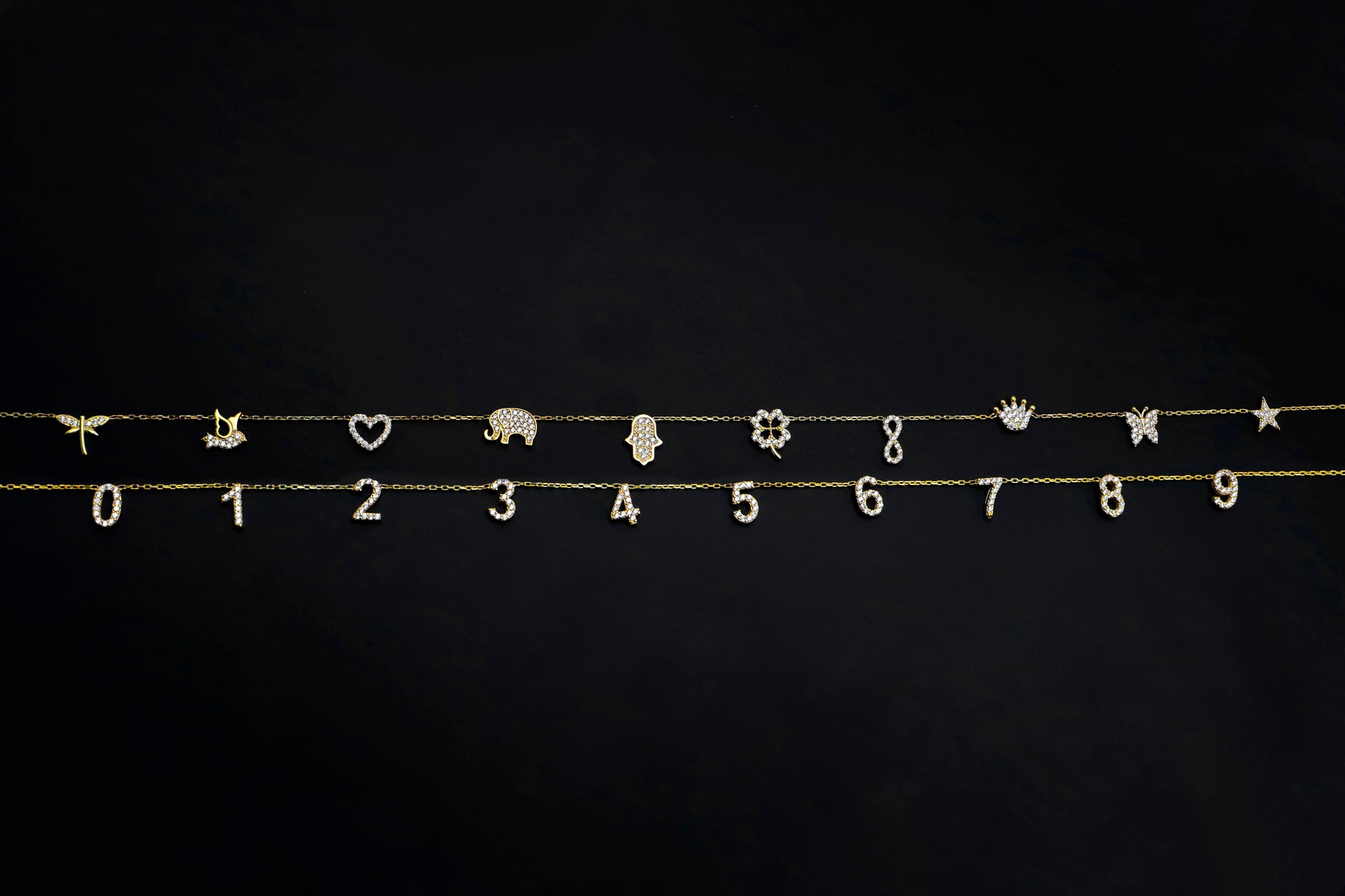 Gold jewelry charms including numbers, animals, and symbols on a black background