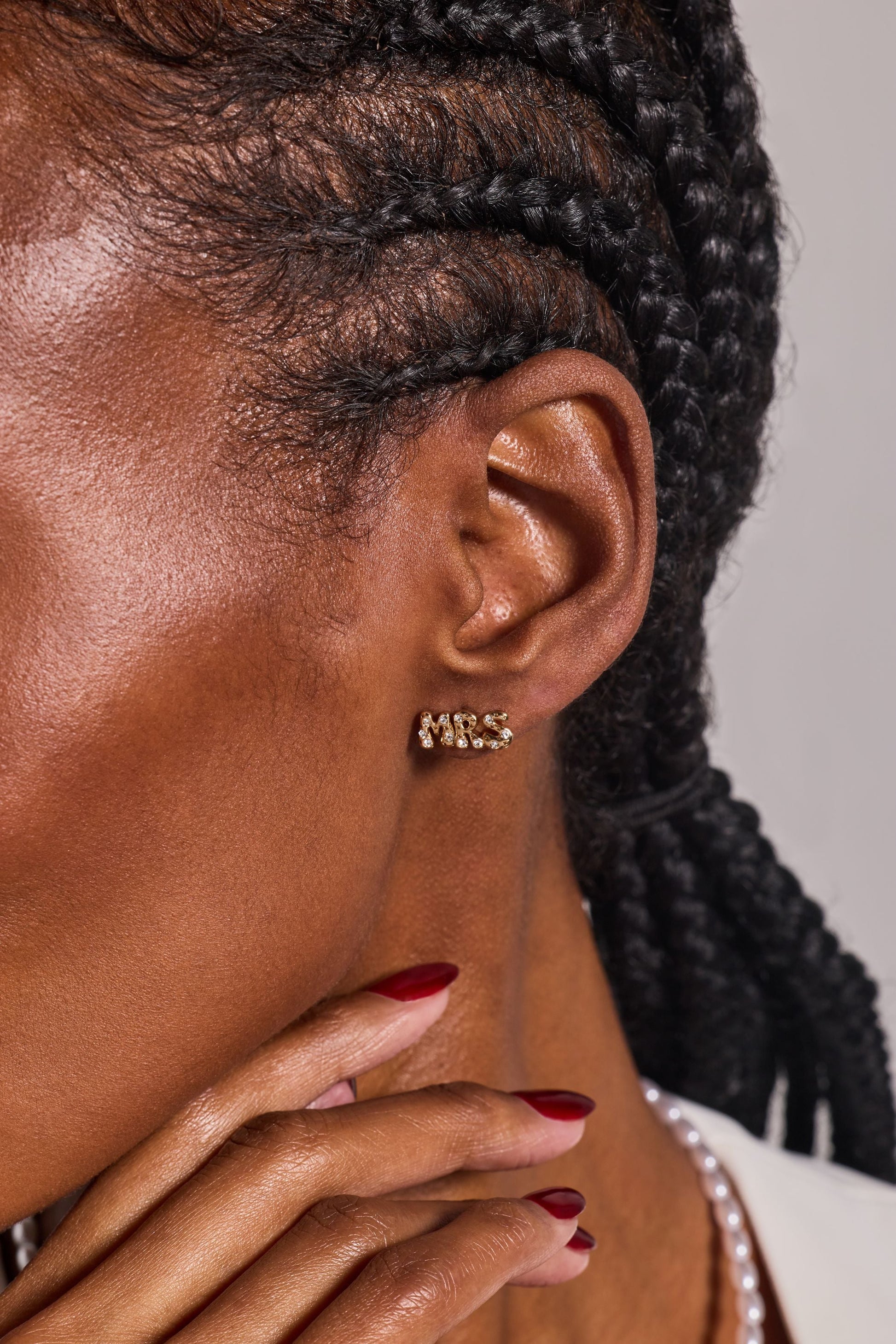 Close-up of a person wearing gold hoop earrings with a neutral background