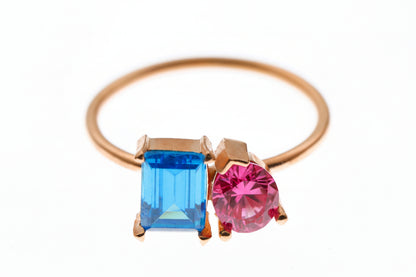 Rose gold ring with blue and pink gemstones on a white background