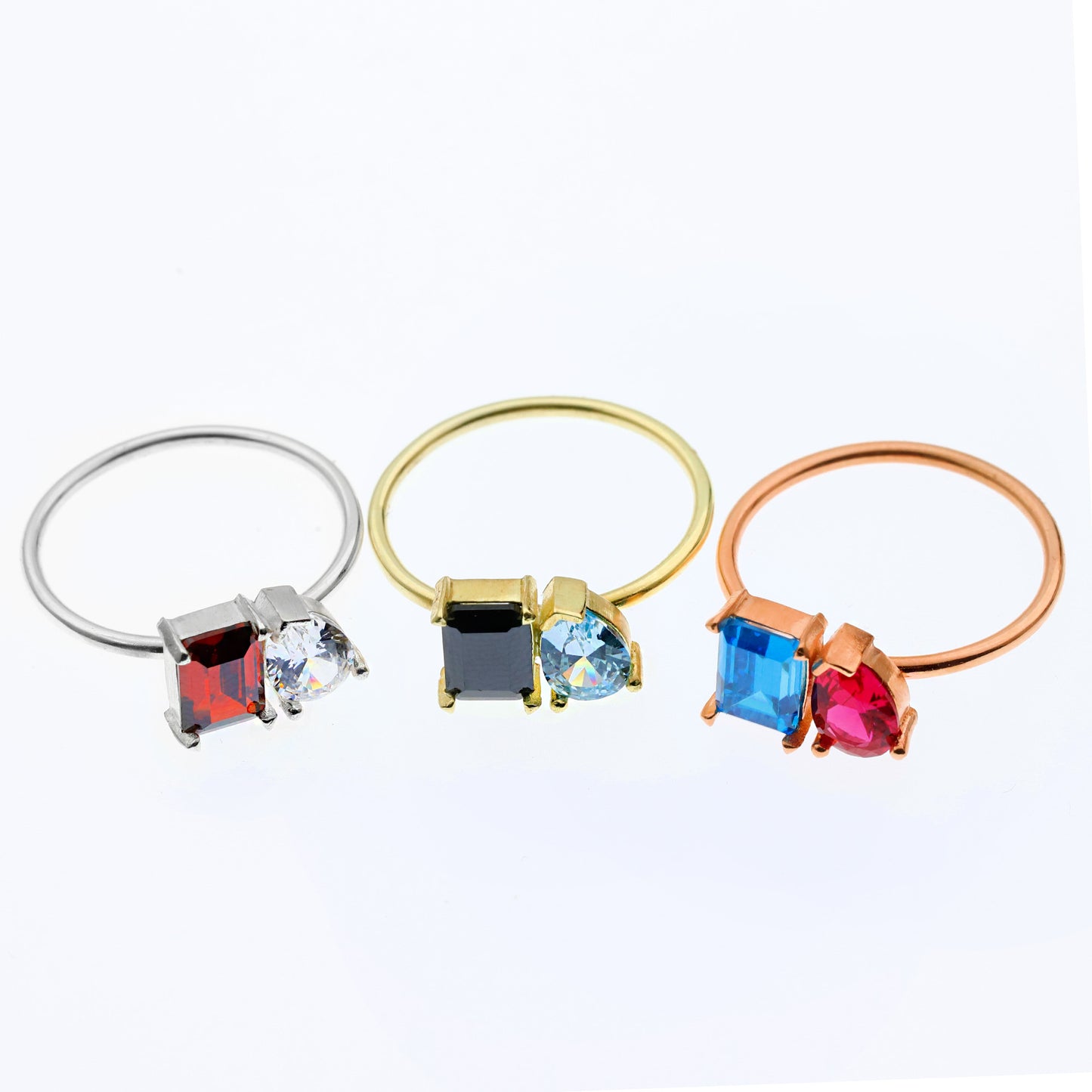 Three ring-shaped jewelry pieces with colorful gemstones on a white background