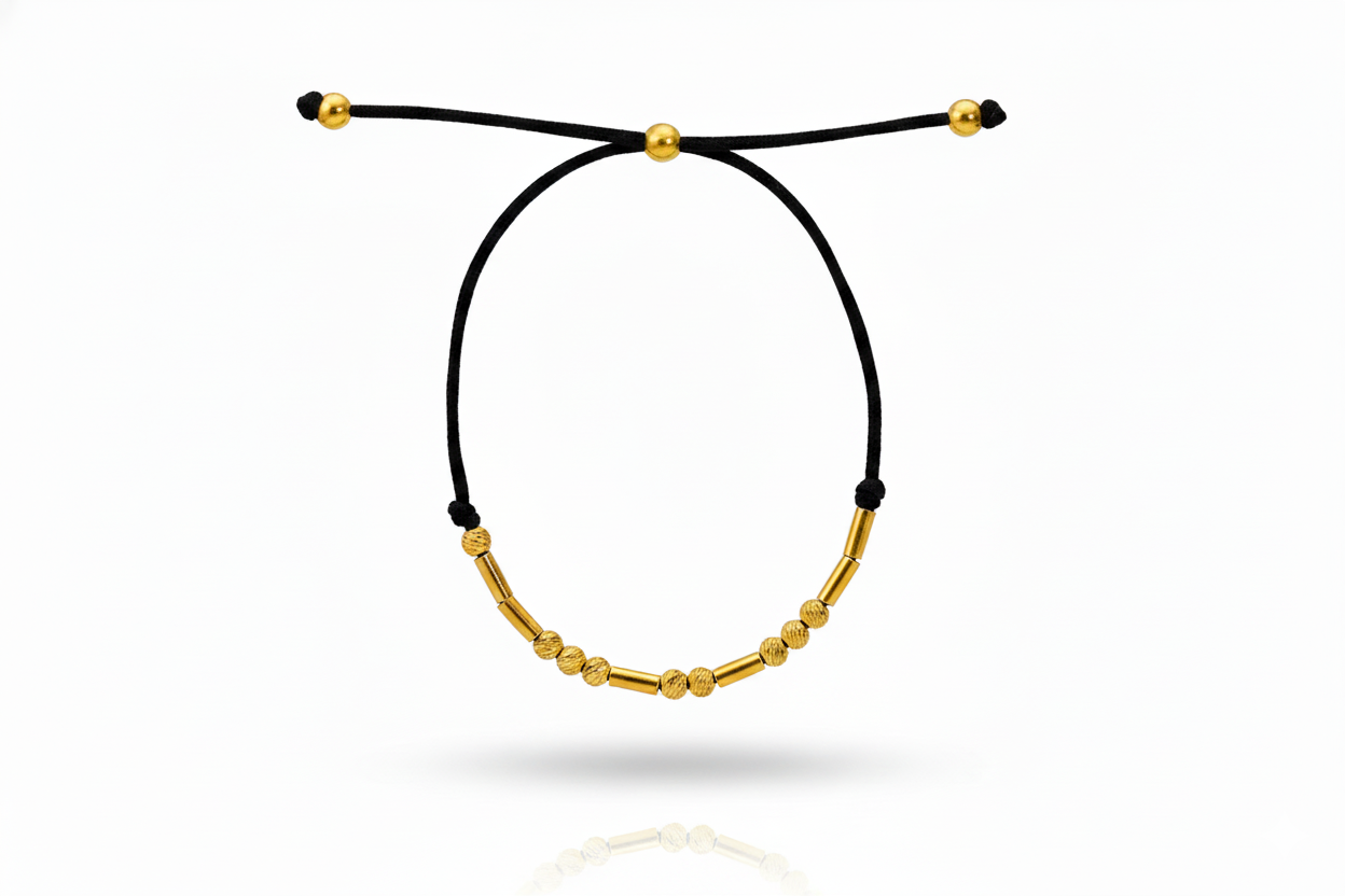 Black cord bracelet with gold beads on a white background