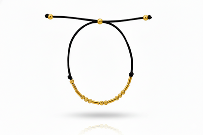 Black cord bracelet with gold beads on a white background