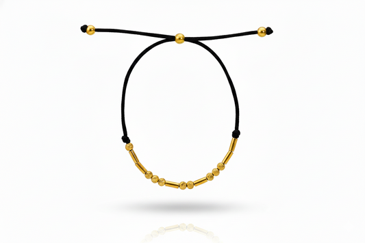 Black cord bracelet with gold beads on a white background