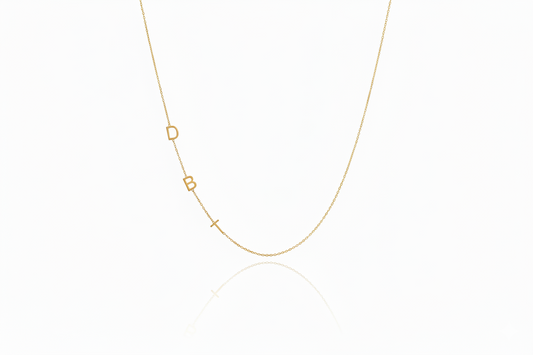 Gold necklace with small geometric pendants on a white background