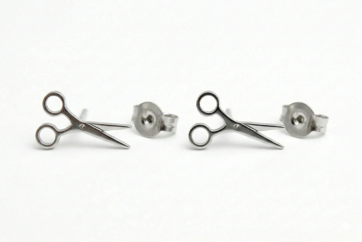 Pair of silver scissors-shaped earrings on a white background