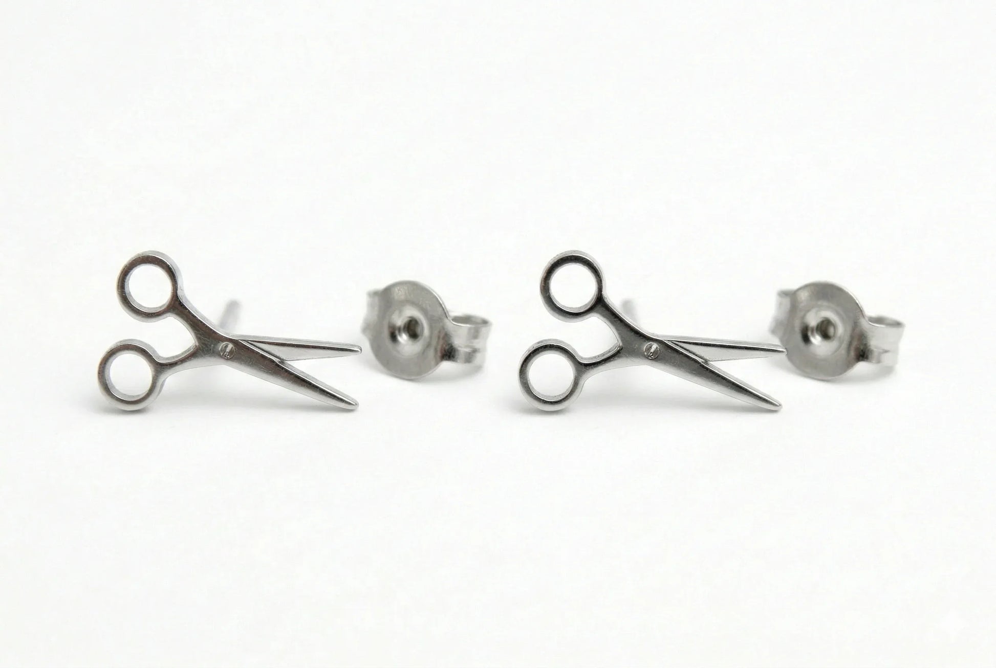 Pair of silver scissors-shaped earrings on a white background