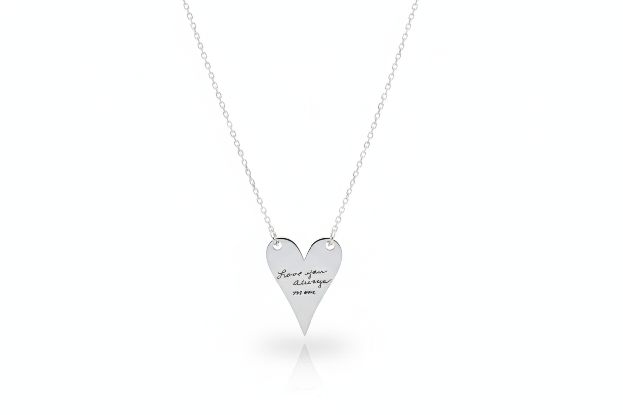 Heart-shaped silver necklace with engraved text on a white background